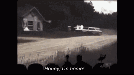 a group of people watching a car race with the words honey i 'm home at the bottom of the screen .
