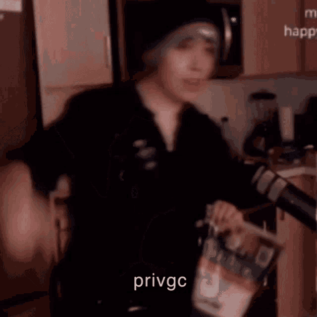 a man wearing a beanie is holding a bag of food in a kitchen .