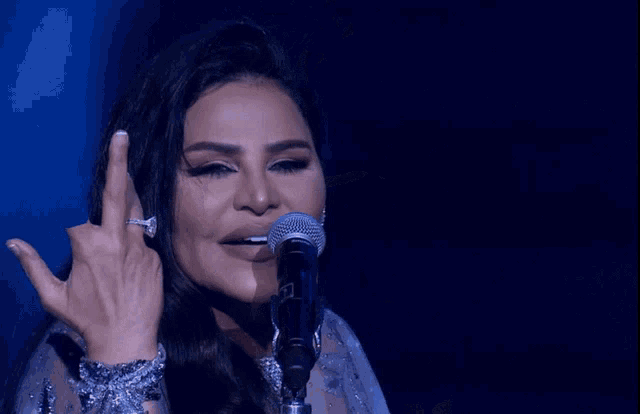 a woman singing into a microphone while making a rock sign