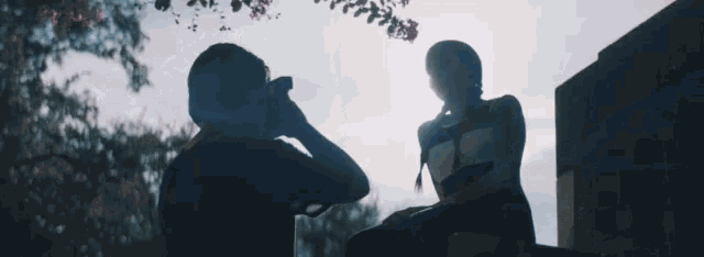 a man is taking a picture of a woman sitting on a ledge