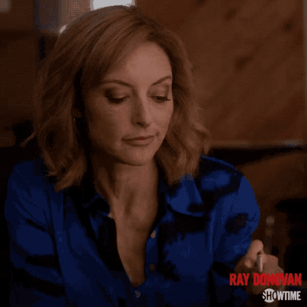 a woman in a blue shirt is smoking a cigarette with ray donovan showtime written on the bottom