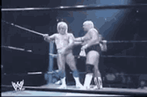 two men are wrestling in a ring and one is holding a sword