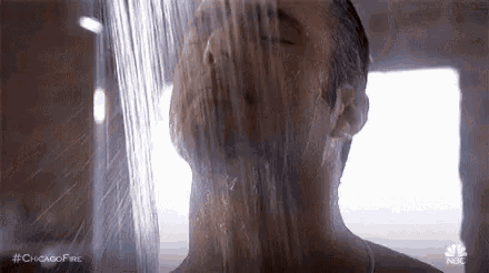 a man is taking a shower with his eyes closed in a shower stall .