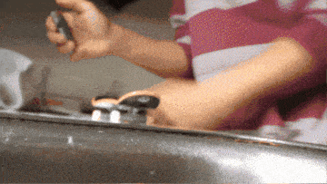 a person in a pink and white striped shirt is holding a screwdriver
