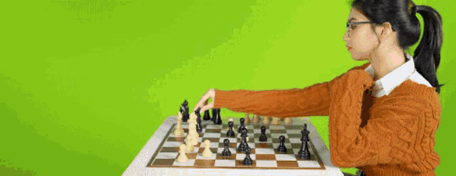 a woman is playing a game of chess against a green background .
