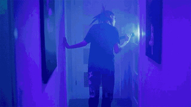 a person with dreadlocks is walking down a hallway in a blue light