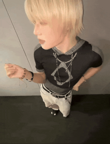 a person with blonde hair is wearing a black shirt with a circle on it