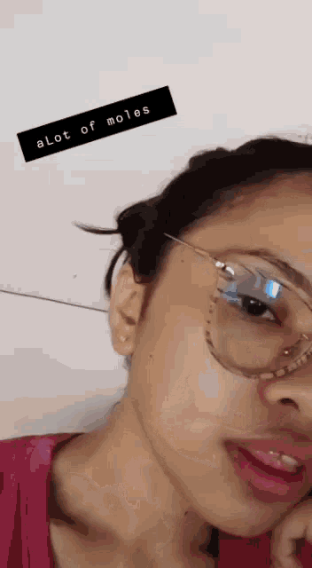 a close up of a woman wearing glasses with a sticker that says alot of moles on it