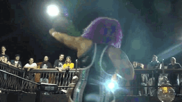a woman with purple hair is standing in front of a crowd at a wrestling match .