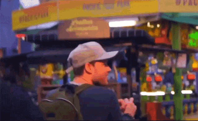 a man wearing a hat stands in front of a yellow sign that says ' arcade ' on it