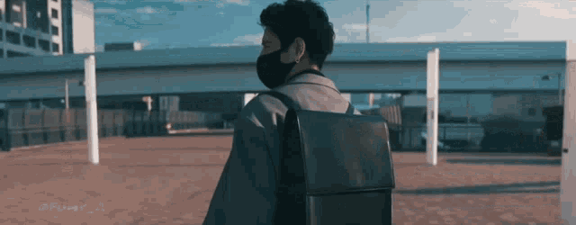a man wearing a black mask and carrying a black bag