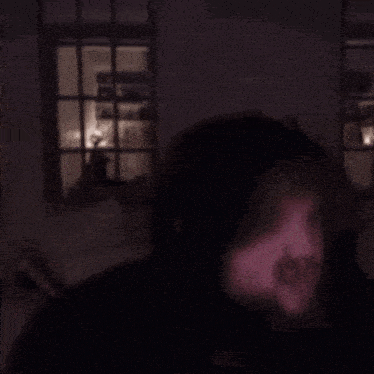 a blurry picture of a person standing in front of a window at night .