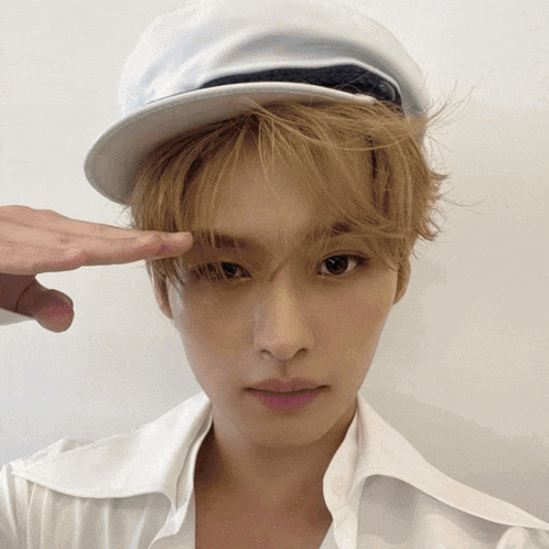 a young man wearing a white hat and a white shirt looks at the camera