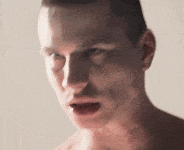 a man without a shirt is looking at the camera with his mouth open