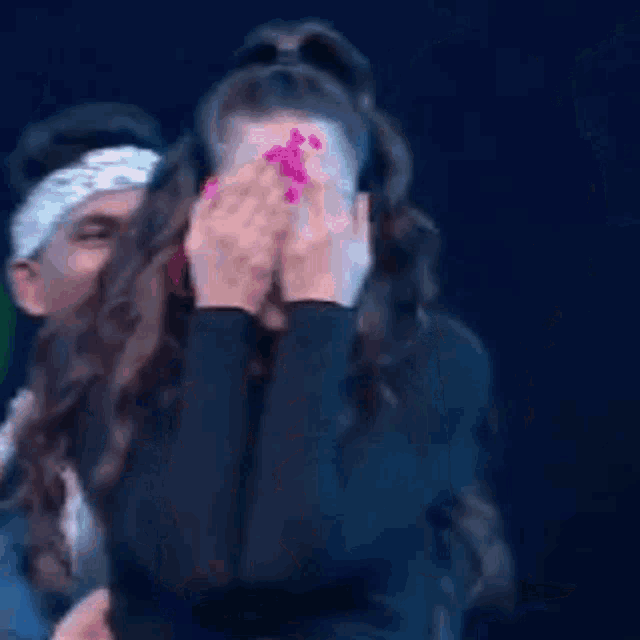 a woman is covering her face with her hands while a man holds her head .