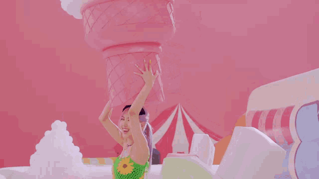 a woman is holding a giant pink ice cream cone on her head