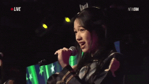a girl singing into a microphone with the words live in the corner