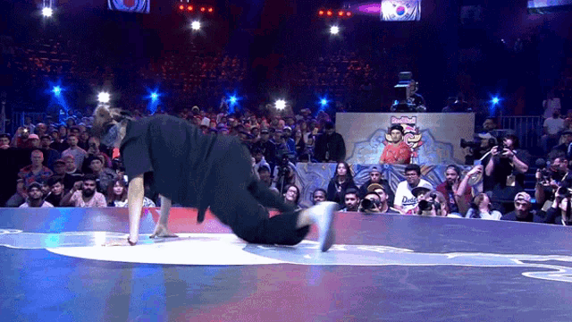 a man is doing a trick on a stage in front of a crowd with a sign that says red bull