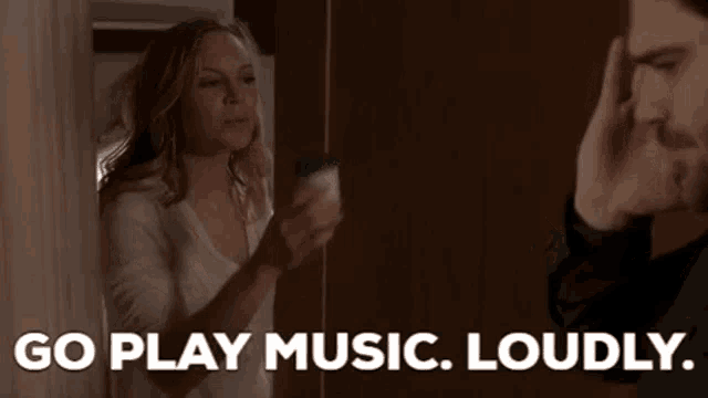 a man and a woman are standing next to each other and the woman is saying `` go play music loudly ''