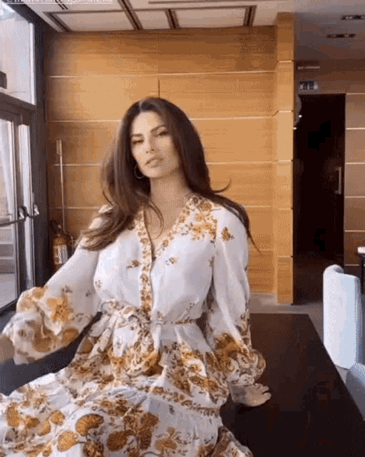 a woman in a floral dress is sitting on a chair in a room .