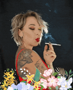 a woman is smoking a cigarette with flowers in the background