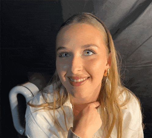 a woman with blonde hair and blue eyes is smiling