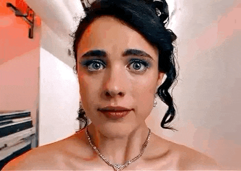 a woman wearing a necklace and earrings is looking at the camera .