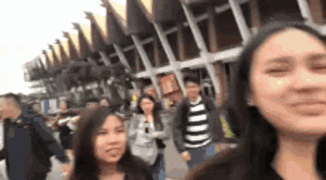 a group of people are standing in front of a building and one of them is making a funny face .