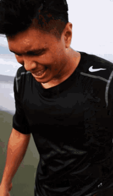 a man wearing a black nike shirt looks down at something