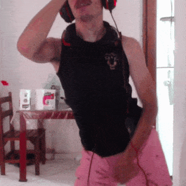 a man wearing headphones and a black tank top with a bull on the front is dancing