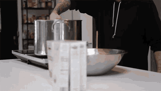 a man in a black hoodie is pouring milk into a bowl