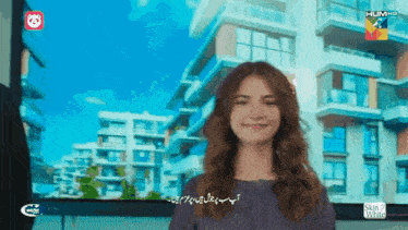 a woman is smiling in front of a screen that says hum hd on it