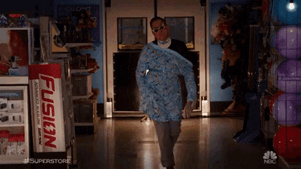 a man is walking down a hallway in a store with a fusion advertisement in the background .