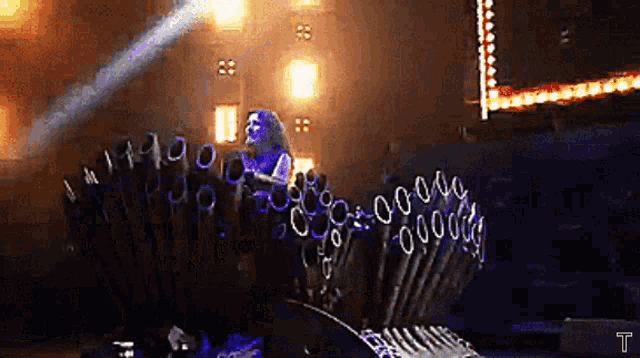 a woman singing into a microphone on a stage with a t on it