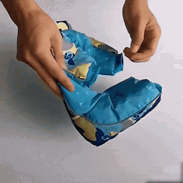 a person is holding a blue and yellow item with a dolphin on it