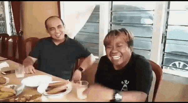 a man and a woman are sitting at a table with food and drinks .