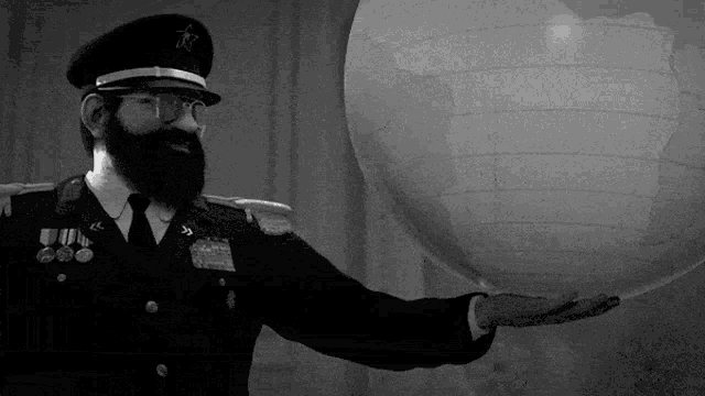 a man with a beard and glasses is holding a globe in his hand .
