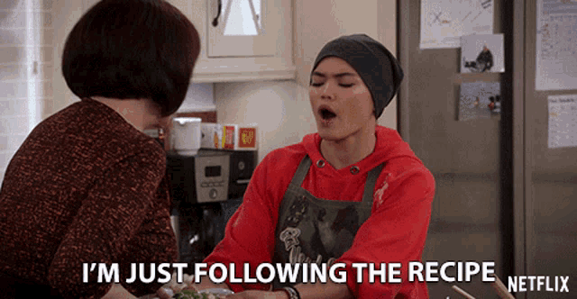 a woman is talking to another woman in a kitchen and says i 'm just following the recipe