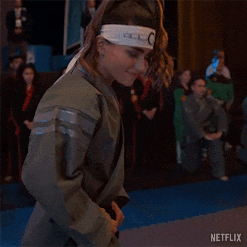 a woman wearing a headband and a kimono is dancing in a dark room .