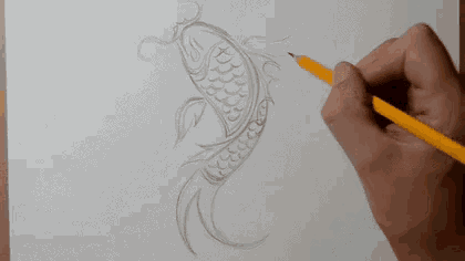 a person is drawing a fish on a piece of paper with a yellow pencil .