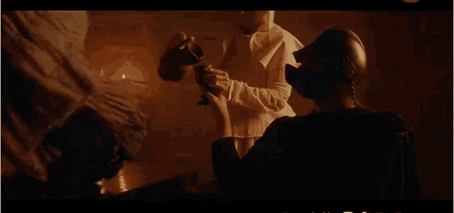 a man in a helmet is holding a cup in front of a woman in a white robe