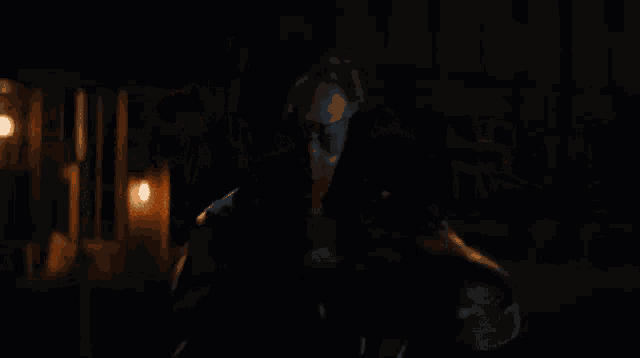 a man is holding a gun in a dark room with a flame coming out of his gun .