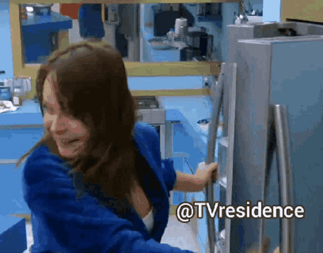 a woman in a blue robe is opening a refrigerator door with the words @tvresidence written below her