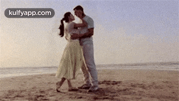 a man and a woman are dancing on the beach near the ocean .