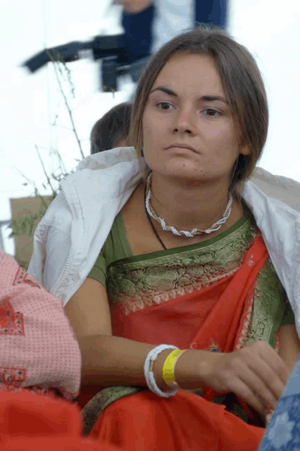 a woman wearing a red and green sari has a yellow wristband on her wrist that says ' i love you '