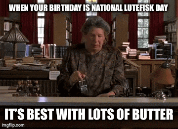 a woman is sitting at a desk in a library holding a glass of butter