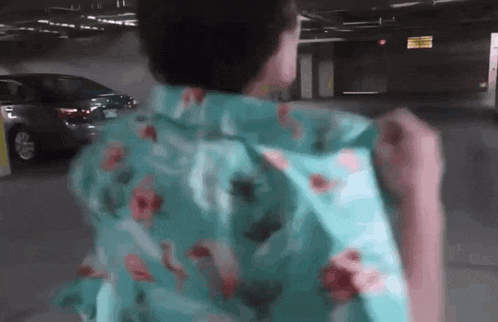 a man in a floral shirt is standing in a parking garage