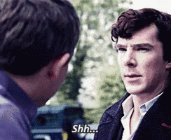 a man in a suit is talking to another man and says shh .
