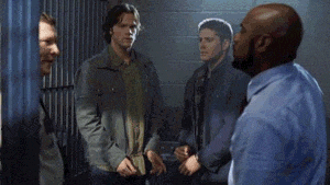 a man in a blue shirt is pointing at another man in a prison cell