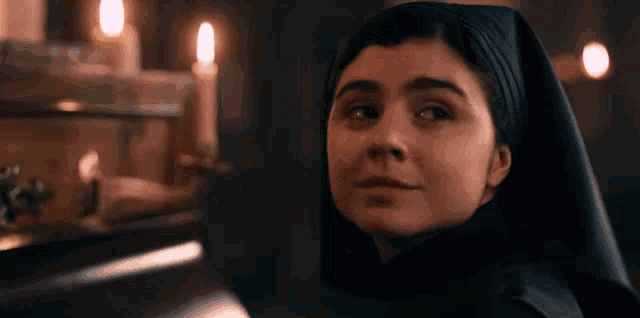 a woman wearing a nun 's cape looks at the camera